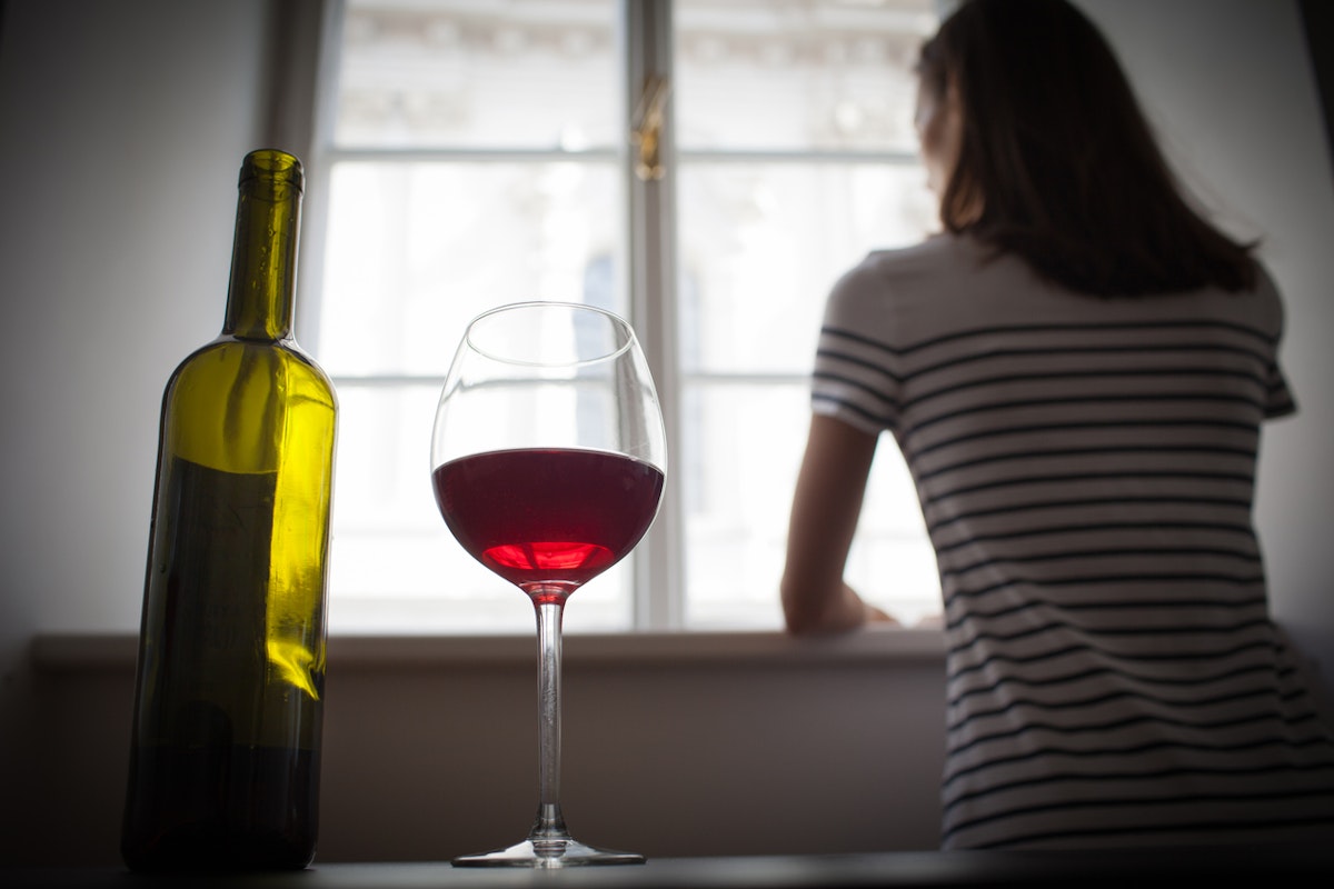 A lady with a bottle and glass of red wine